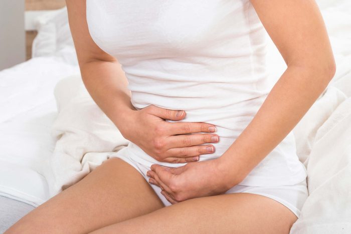 woman in a white t-shirt holding her stomach