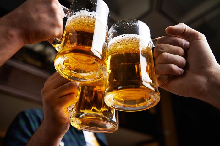 hands clinking together three mugs of beer in a toast