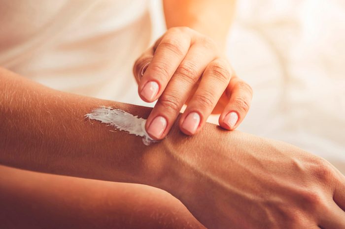 close up of a woman's hands as she applies lotion to her wrist
