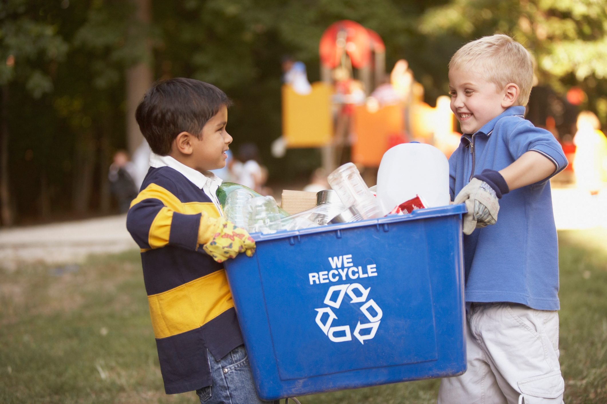 two little boys carrying a blue recycling bin