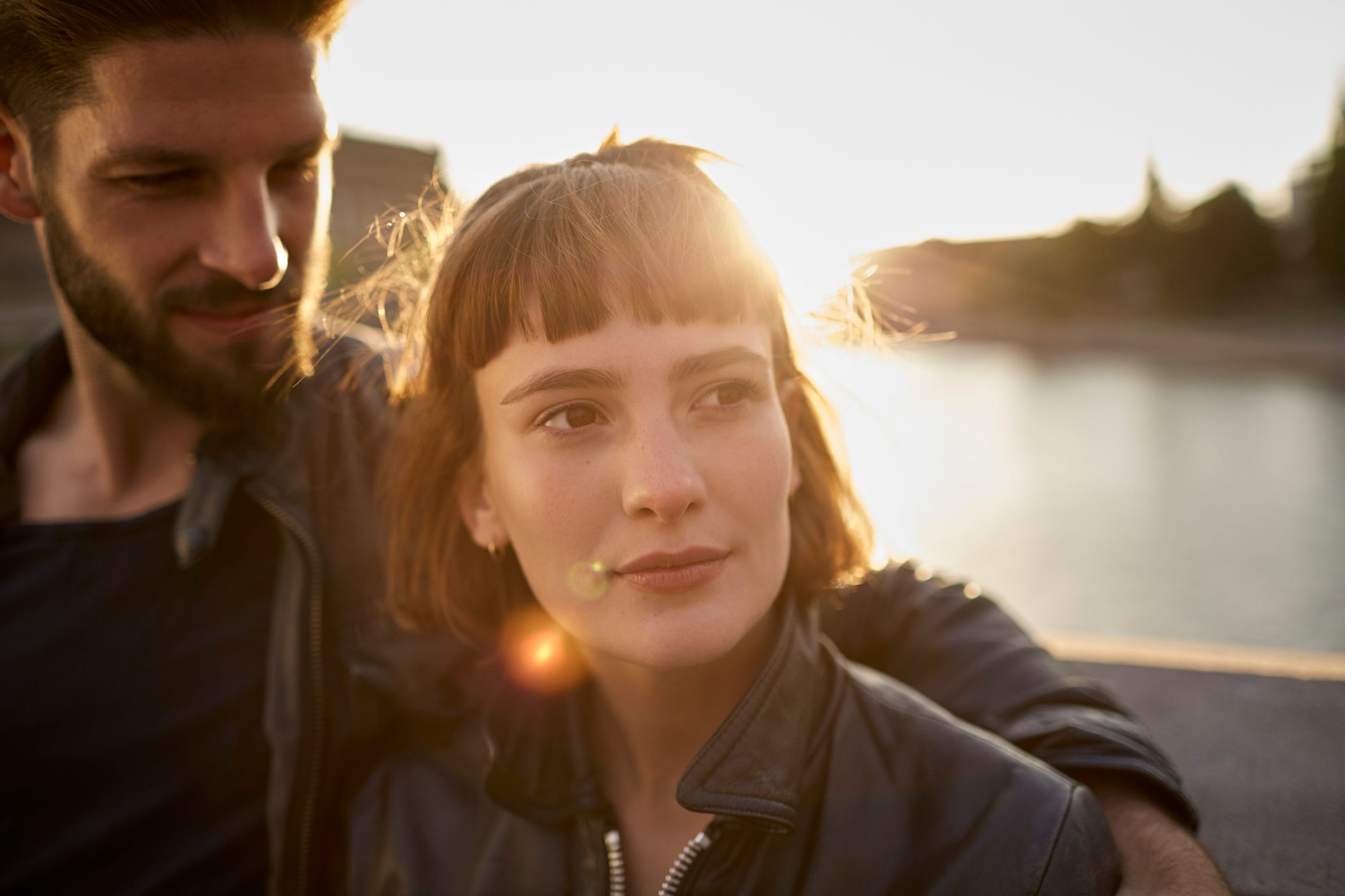 Young couple in backlight by the riverside
