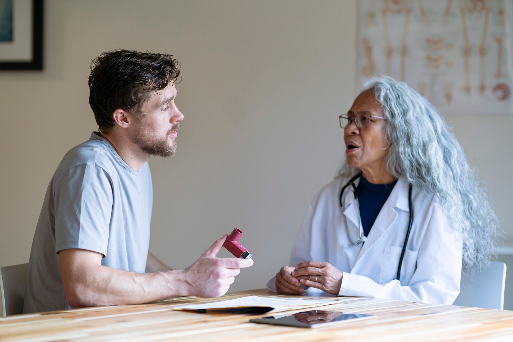 Man in medical consultation discusses with his doctor using a puffer inhaler for asthma
