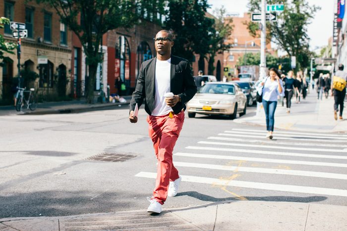 Man walking in the street, holding cup of coffee
