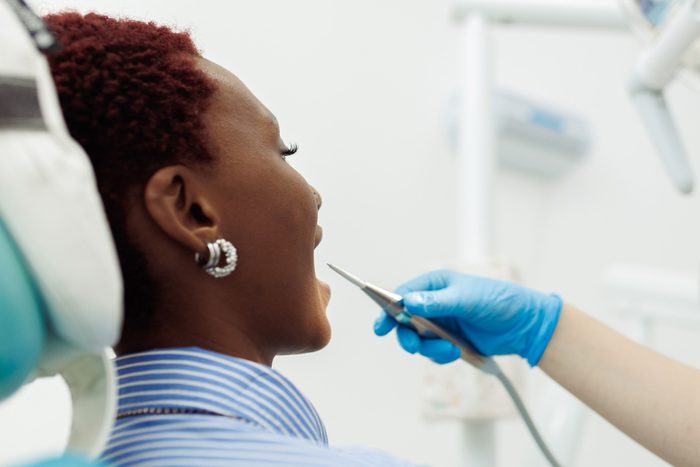 woman in dentist's chair with laser near her mouth